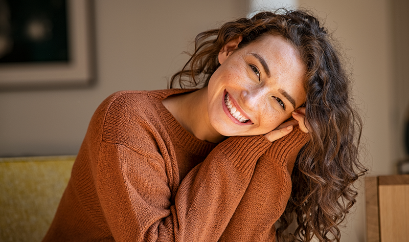 A warm lifestyle portrait of a woman with radiant, clear skin, illustrating the natural benefits of a consistent longevity supplement stack for maintaining cellular health.